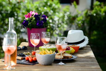 holiday summer brunch party table outdoor in a house backyard with appetizer, glass of rosé wine, fresh drink and organic vegetables