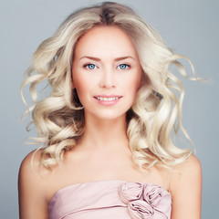 Perfect Blonde Woman with Blowing Blonde Curly Hair and Prom Dress. Fashion Model with Wavy Hairstyle