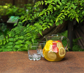 Refreshing fruit water in the decanter outdoors in the garden.