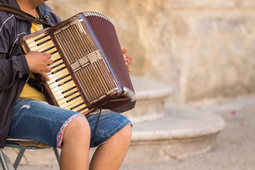 Matera, Italy - May 20, 2017: Street musician plays an old accordion sitting