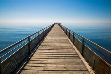 Fototapeta premium A path to infinity. Long seaside pier reaching the sky.