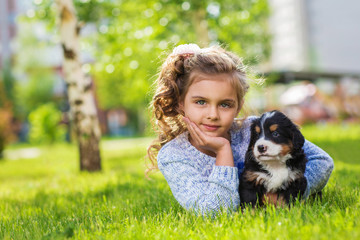 Little girl with a berner sennenhund puppy, outdoor, summer