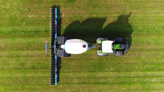 Aerial top down view of farmer liquilising fertilizing grass field with specialized farming equipment made to improve and losening soil under grass big white trailer with liquid for getting soil wet