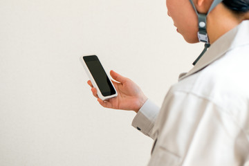 スマートフォンを見る女性作業員