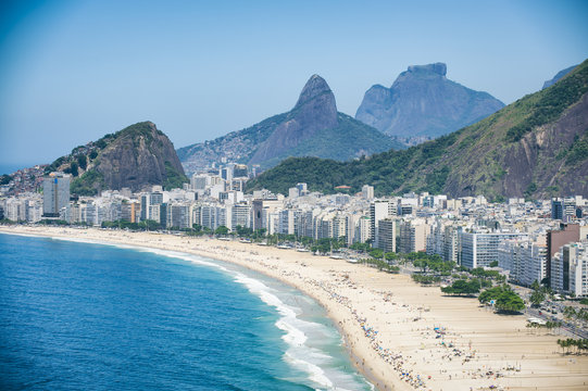 Bright scenic view of the Rio de Janeiro, Brazil skyline overlooking the shore of Copacabana Beach and dramatic mountains in the background