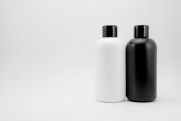 Black and white cosmetic skin care containers and charcoal raw soap package on white isolated background.
