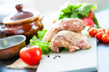 Marinated chicken meat, ceramic pot and vegetables 