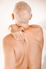 Man massaging his top back, the trapezius muscle, because of a thoracic vertebrae pain due to a...