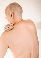 Man massaging his top back, the trapezius muscle, because of a thoracic vertebrae pain due to a...