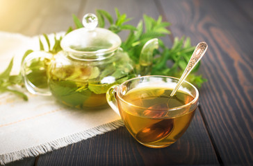 Cup of mint tea and a bunch of mint on the table.