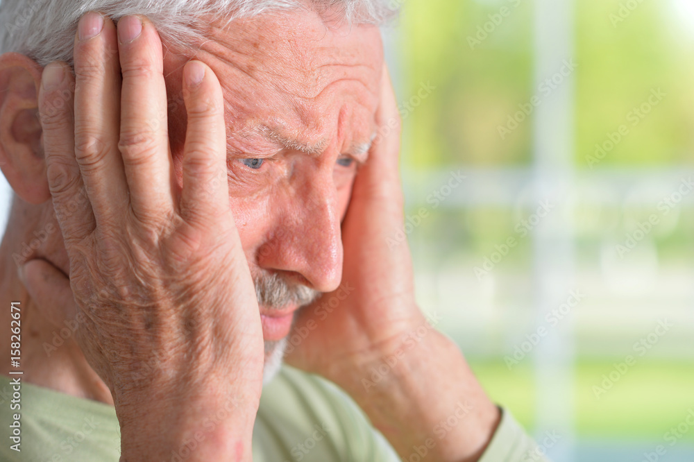 Wall mural Old sad man on the window background