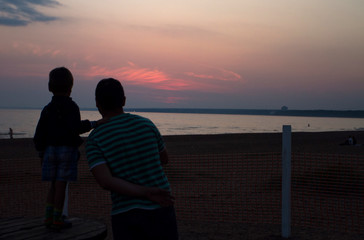 Silhouettes of a father and son at sunset at the sea shore