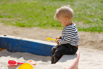 One year old baby boy toddler at playground sandbox