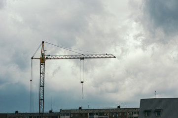 Crane over a cloudy sky background. Construction in the city. Industry.