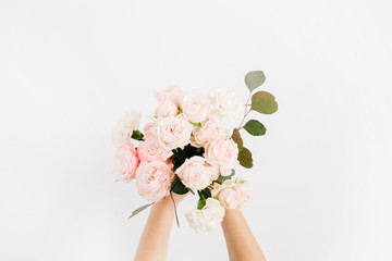 Beautiful pink rose flower and eucalyptus branches bouquet in girls hand isolated on white background. Flat lay, top view. Floral composition