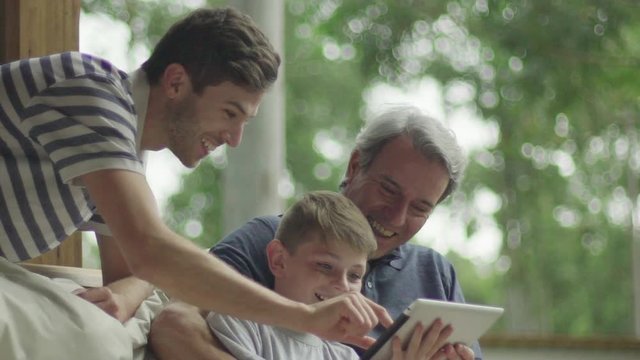 Boy with father and grandfather using digital tablet