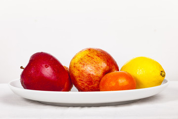 mixed fresh fruits on a white plate