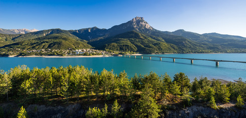 Summer panoramic view of Serre-Poncon Lake with Savines-le-Lac, its bridge and the Grand Morgon mountain peak. Hautes-Alpes, PACA Region, Southern French Alps, France