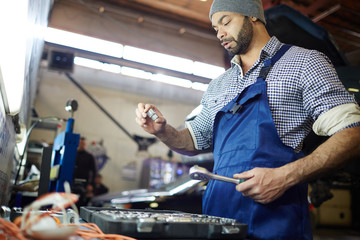 Young mechanic in uniform working in garage