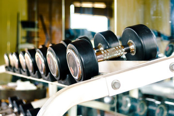 Obraz na płótnie Canvas Rows of dumbbells in the gym with high contrast and warm color tone