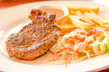 Tasty grilled steak with french fries and vegetables