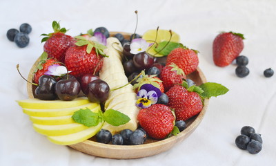 Wooden plate with fruits and berries, blueberries, strawberries, cherry, apple, banana, healthy breakfast