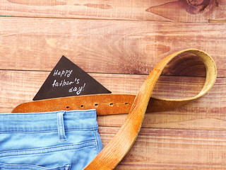 Happy Father's Day the leather strap on wooden background. Greetings and presents