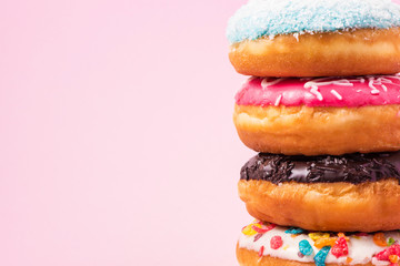 Donuts with icing on pastel pink background with copyspace. Sweet donuts.