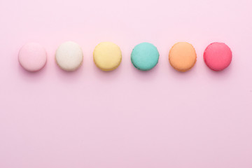 Colorful pastel cake macaron or macaroon on pink background from above