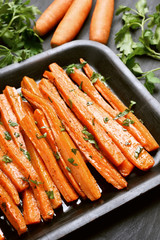 Carrots with green herbs in baking tray