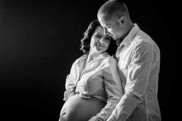 Romantic moments for pregnant couple, man kiss pregnant woman and hold big belly black and white photo