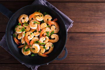 Shrimp Scampi traditional dish on wooden background top view. Shrimp fried in garlic batter with lemon and parsley. Healthy food. Clean eating. Space for text.
