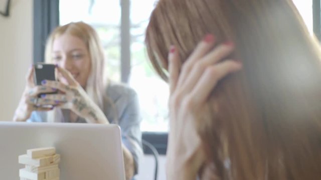 Woman twirling hair while friend takes picture