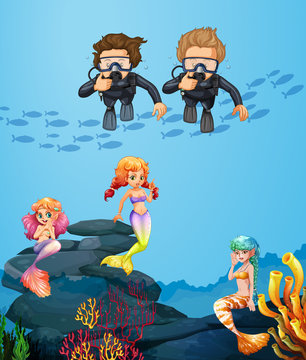 People diving underwater with mermaids