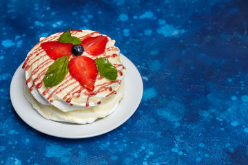 White creamy round cake with strawberries and mint on plate