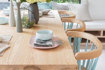 wooden dining table in modern dining room with table set and vase of plants