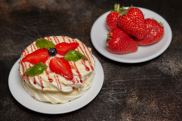 White creamy round cake with strawberries and mint on plate