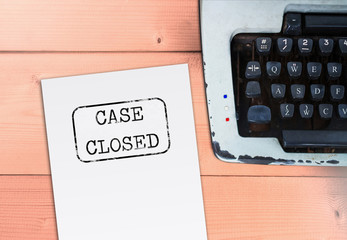 Case closed on paper with typewriter on wooden table