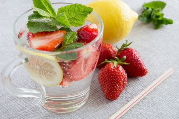 Detox water with strawberry, lemon and mint in the glass on the grey background