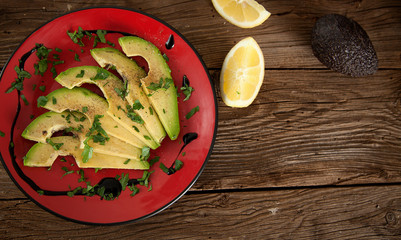 Avocadoscheiben auf Teller mit Dressing und Zitronenstücken