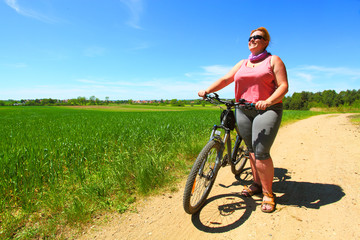 Obraz premium Overweight woman and bicycle. Active people enjoying summer holidays on countryside. 