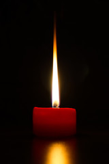 Small red candle with long flame isolated on black