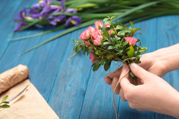 Female florist making floral composition on wooden table
