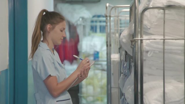 Woman taking inventory of towels in hotel laundry room