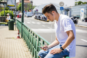 Close up of Young Man Listening to his Favorite Music Using Earphone in City Environment, Using MP3 Player or Smartphone