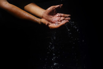 Human Hand Capturing The Water That Is Flowing With Motion Blur Effect Over Black Background
