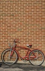 Fototapeta na wymiar red retro bicycle leaning up against a brick wall