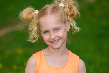 Naughty girl 7 years old portrait. The child laughs merrily. The girl in the orange dress. The concept of a happy childhood. Blonde is a trendy hairstyle.