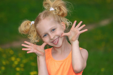 Naughty girl 7 years old portrait. The child laughs merrily and shows language. The girl in the orange dress. The concept of a happy childhood. Blonde is a trendy hairstyle.