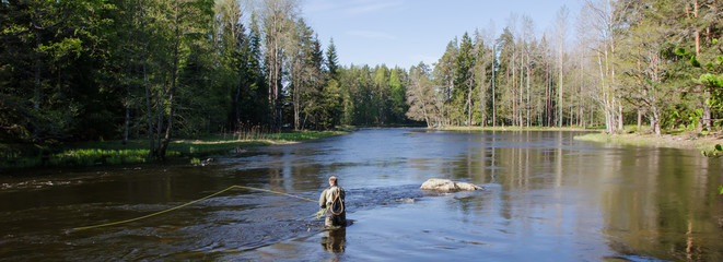 Pêcheur à la mouche utilisant une canne à pêche à la mouche dans une belle rivière au printemps